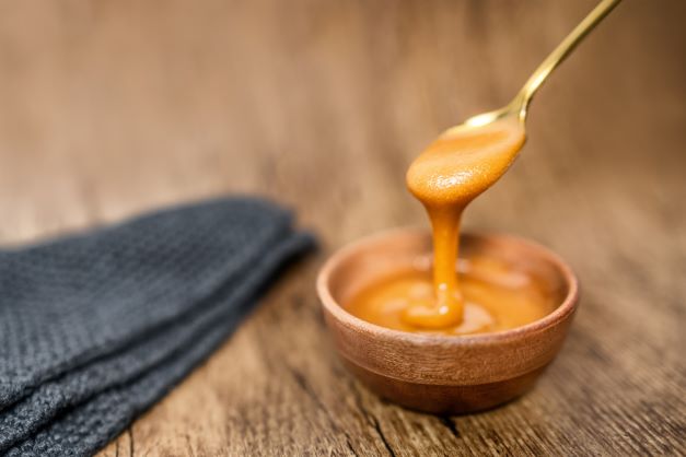 Mānuka honey in bowl on table ready for consumption from spoon.